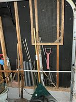 Overall view of yard tools, mesh rolls and framed screen against wall studs