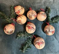 All eight papier-mâché ornaments arranged with artificial greenery