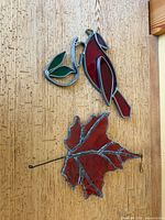 Bird and maple leaf stained glass pieces hanging on wood background