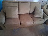 front view of beige three-seat sofa with cushions and pillows