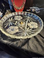 Oblique view of clear pressed glass cake stand showing floral and starburst pattern and pedestal