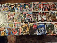 Tabletop view of approximately two dozen bagged comic books laid out in rows