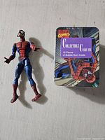 Spider-Man action figure beside sealed Spider-Man candy tin