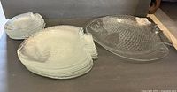 Stack of eight small fish plates beside large fish platter