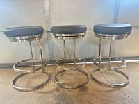 Front view of three matching bar stools showing frames, seats, and footrests