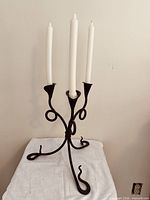 Front view of wrought iron candelabra with three white candles