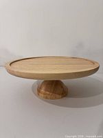 Side view of wooden rotating cake stand showing pedestal and shallow rim