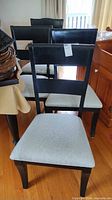 Front view of two chairs showing black wood frames and gray fabric seats