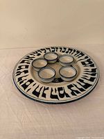 Oblique view of Seder plate with five bowls showing Hebrew lettering and blue trim