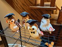 Four graduation owl plush toys on shelf