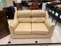 Front view cream leather loveseat showing cushions and arms