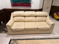 Front view of cream leather three-seat sofa showing overall design and condition
