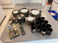 Stacked plates, bowls, mugs, boxed cheese set and butter knife on countertop
