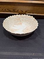 Side view of scalloped-edge pottery bowl showing dove motif and glaze