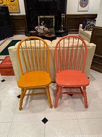 Front view of both Windsor chairs showing yellow and orange paint, spindle backs, turned legs, stretchers