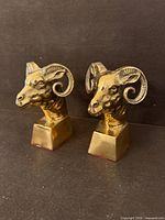 Front view of both brass ram head bookends showing detailed faces and bases