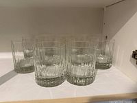 Front view of the ten faceted clear glass tumblers on shelf