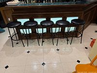 Five matching bar stools lined along bar, full view