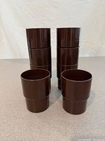 Set of eight brown plastic Sarvis cups stacked in two columns with three additional cups in front
