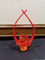 Front view of orange-red Chalet art glass basket with crossed handles
