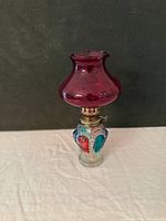 Full view showing red glass chimney, colored glass font, brass burner