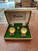 Open case showing pair of cufflinks and stud on green velvet insert