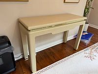 front angled view of console table showing cream grasscloth finish and brass inlay