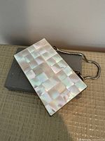 Front view of mother-of-pearl mosaic compact with snake-chain handle