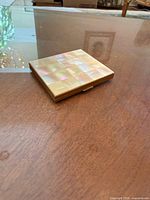 Closed compact showing mother-of-pearl checker pattern lid