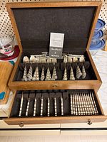 Chest open showing upper tray with grouped spoons, forks and knives plus drawer with steak knives and seafood forks