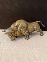 Left side view of brass charging bull figurine