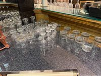 Countertop view of assorted clear glasses, mainly rocks glasses and small stemware