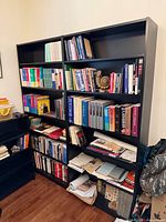 Front view of both matching black bookcases filled with assorted books and items (contents not included)