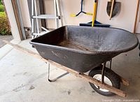 Full side view of wheelbarrow showing tray, handles, frame and tire
