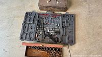Overview of open plastic tool case, red toolbox with sockets, closed brown toolbox
