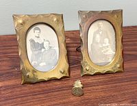 Two hammered brass frames with photos and bronze wax seal on tabletop