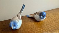 Both Titmouse figurines side by side on wood surface