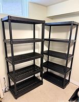 Two matching black plastic shelving units side by side, five tiers each