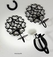 Two scroll design sconces and disassembled horseshoe sconces on surface