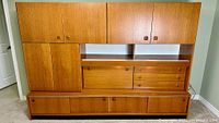 Front view of complete teak wall unit showing cabinets, drawers, shelf