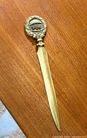 Full view of bronze letter opener on wood surface