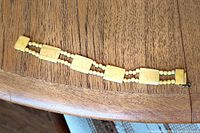 Full view of bracelet laid flat showing panels and bead strands