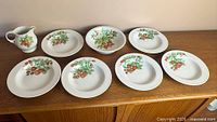 Full set on wooden surface: creamer, serving bowl, six plates