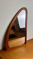 Front view of asymmetrical teak mirror showing entire frame and glass