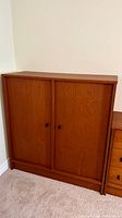 Front view of teak cabinet showing two sliding doors and circular pulls