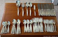 Entire 75-piece WM Rogers Sweep flatware set laid out