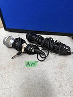 Black and silver microphones with coiled cords and 1/4-inch plugs displayed on surface