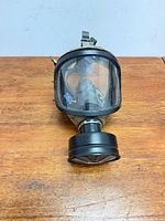 Front view of full face gas mask with attached canister showing visor and filter