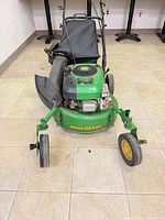 Front view of mower showing deck, engine, chute, wheels, branding