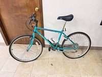 Full view of Schwinn teal bicycle leaning against wall
